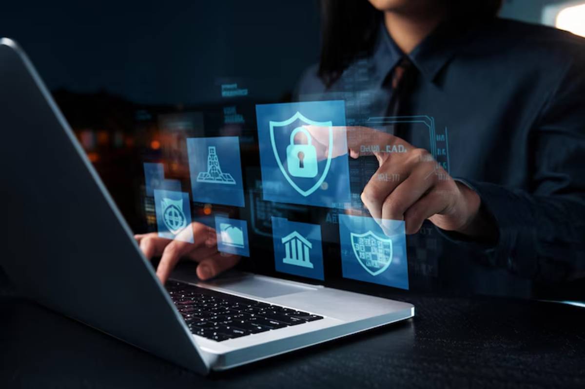 A business professional analyzing cybersecurity icons on a laptop screen in a dimly lit environment, focusing on a shield with a lock.