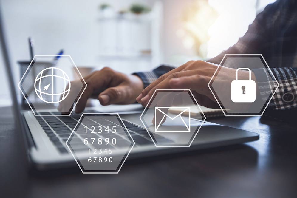 A close-up of hands typing on a laptop, with icons representing globe, email, and lock overlaying the image, suggesting online security.