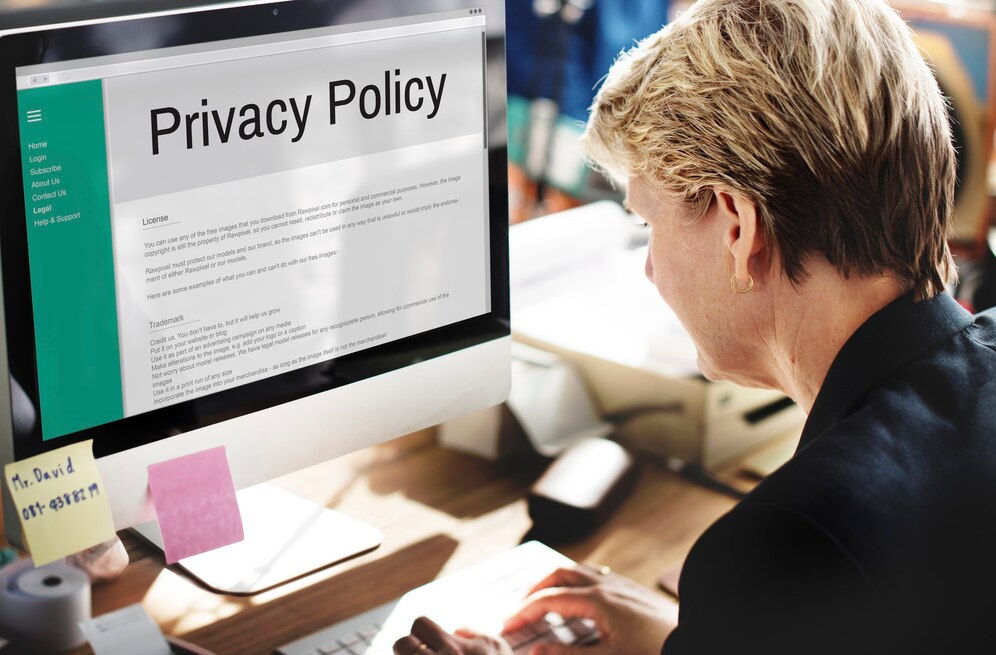 A person reviews a Privacy Policy on a computer screen with sticky notes on the desk, emphasizing a professional work environment.