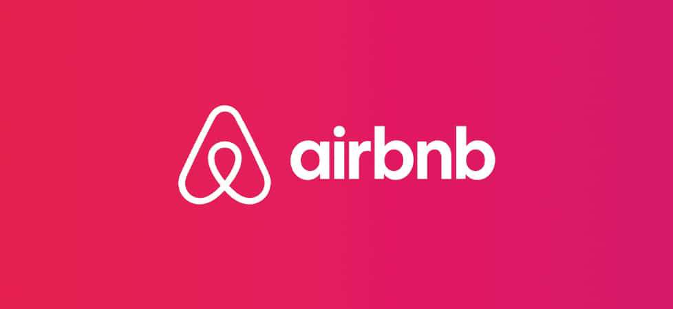 Airbnb logo featuring a stylized heart and home symbol in white against a vibrant pink gradient background.