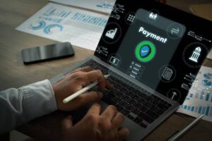 A person using a laptop with a digital payment interface and security features, surrounded by financial data and graphs.