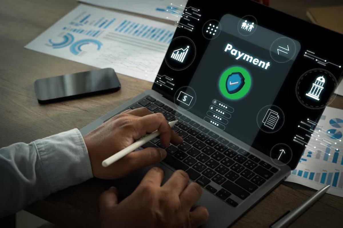 A person using a laptop with a digital payment interface and security features, surrounded by financial data and graphs.