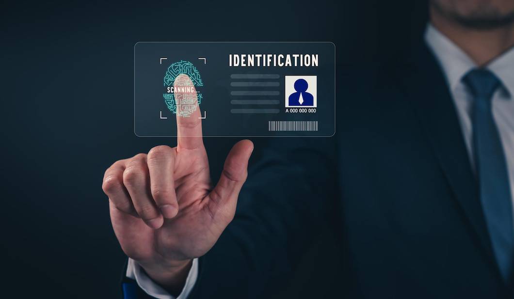 A man in a suit scans his fingerprint on a digital ID card displaying IDENTIFICATION and SCANNING against a dark background.