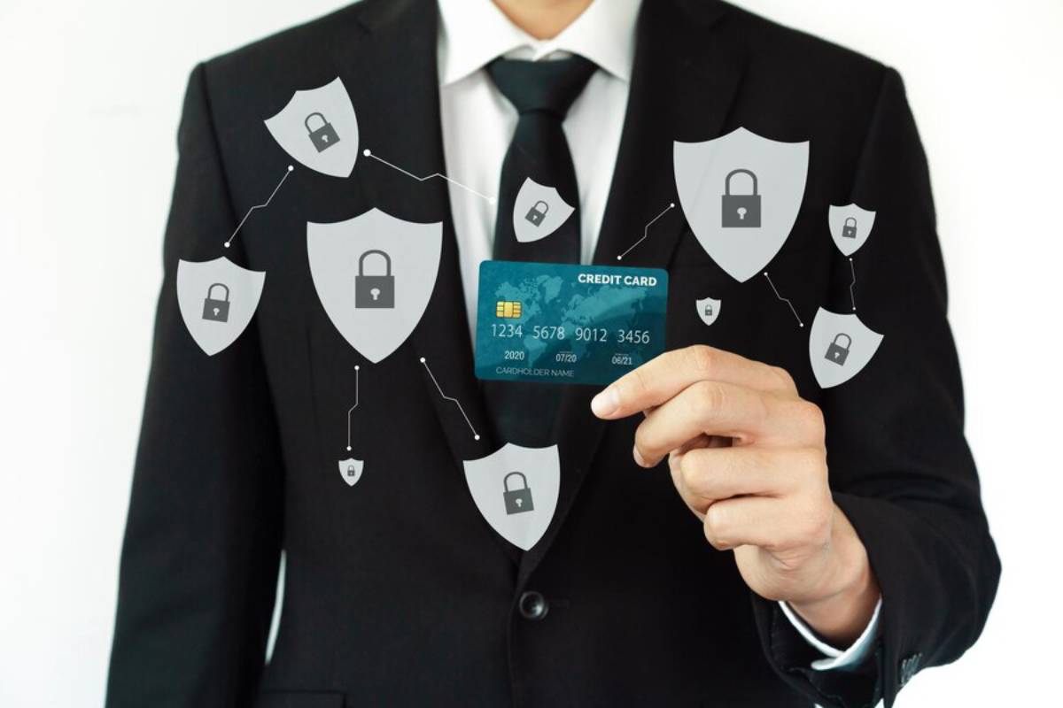 A businessman in a suit holds a credit card, surrounded by graphic shields with locks, symbolizing security and credit protection.