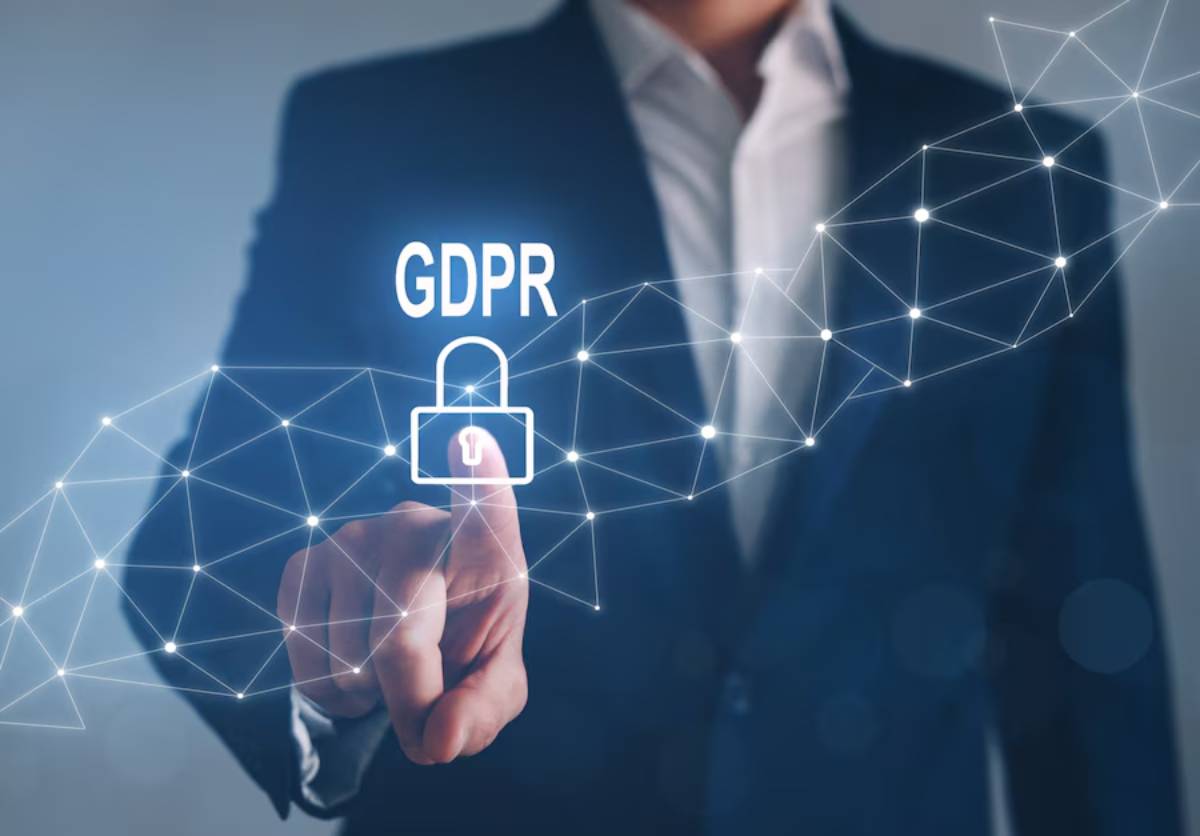 A businessman in a suit pressing a virtual button labeled GDPR with a padlock icon, symbolizing data protection and privacy.