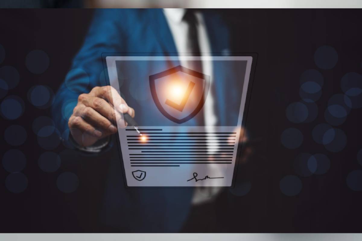 A businessman in a blue suit is digitally signing a document with a shield icon and checkmark, symbolizing security and validation.