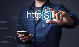 A person in a dark shirt holds a smartphone, highlighting https with a padlock symbol, symbolizing online security.