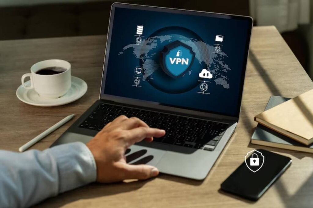 A person using a laptop displaying a VPN interface, with coffee, a notebook, and a smartphone on a wooden desk.